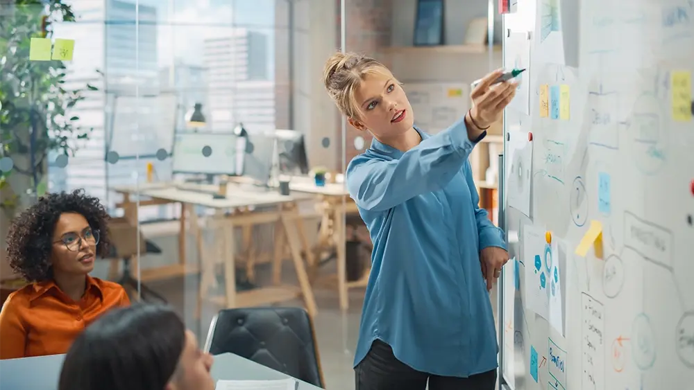Frau erklärt etwas auf Whiteboard